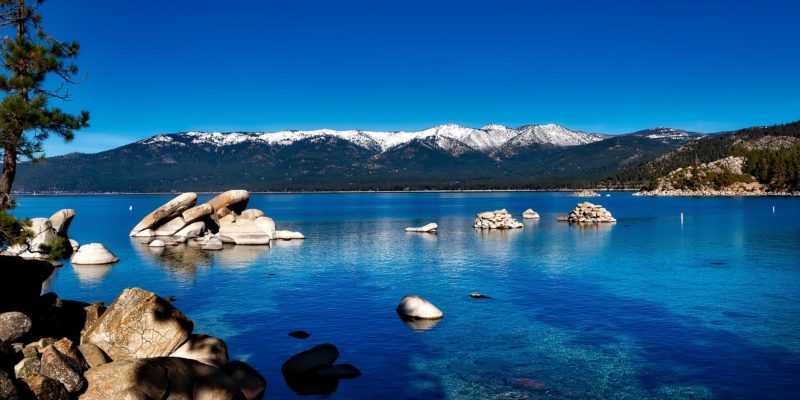 Blue sky, blue water, snow capped mountains in the background
