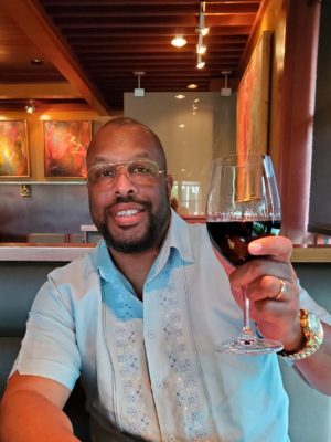 Recruiter Antwan toasts with red wine while sitting in a darkened restaurant