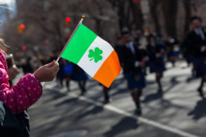 Irish flag in front of a darkened parade in the background