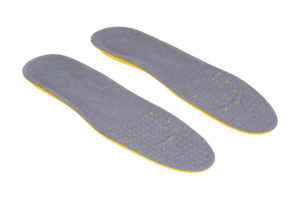 Grey shoe inserts with yellow bottoms sit on white floor